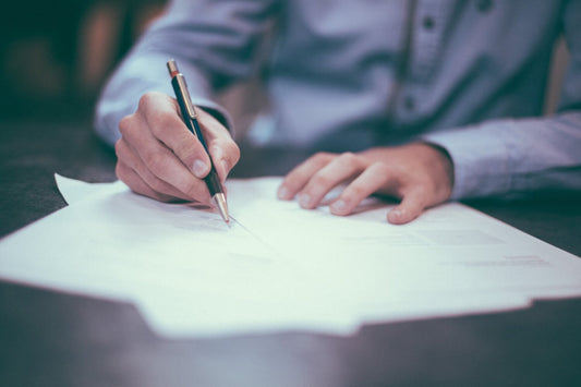 man's hands at desk writing on paper