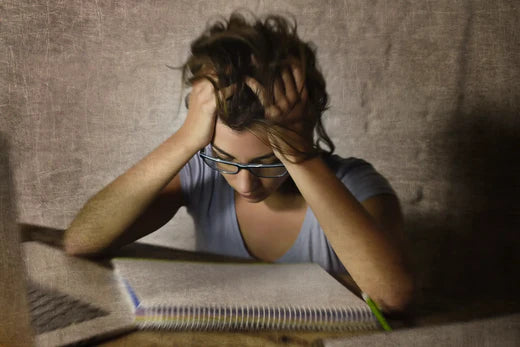 woman holding head staring at notebook