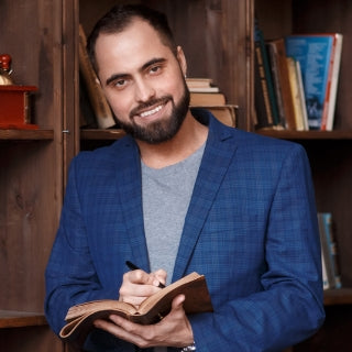 Mature indian man smiling and holding book and pen